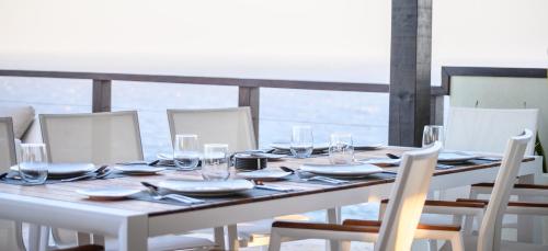 a wooden table with chairs and plates and wine glasses at Villa Topaz Above West Bay With 360 Degree Views! 3 Bedrooms in West Bay