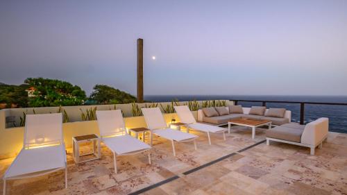 a patio with chairs and a table and a couch at Villa Topaz Above West Bay With 360 Degree Views! 3 Bedrooms in West Bay