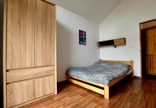 ロビにあるDomki na Rozanejのベッドルーム1室(ベッド1台付)、木製キャビネットが備わります。
