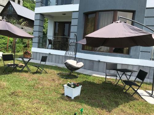 a yard with chairs and an umbrella and a swing at Guest House Botanical Paradise in Mtsvane Kontskhi