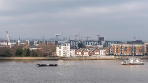 zwei Boote auf einem Fluss mit einer Stadt im Hintergrund in der Unterkunft LT Riverview Apartments East Greenwich in Woolwich