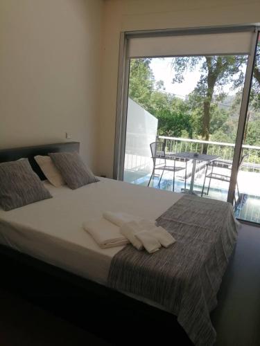 a bedroom with a bed with white pillows and a large window at Fonte dos Amores - Alojamento in Caniçada