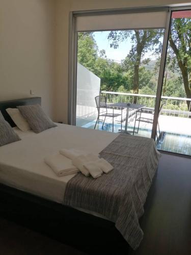 a bedroom with a bed and a large window at Fonte dos Amores - Alojamento in Caniçada