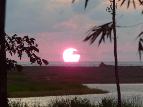 a sunset on the beach with the sun in the horizon at Encanto Lodge in Drake
