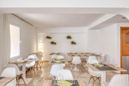 uma sala de jantar com mesas e cadeiras brancas em Hotel Torá em Paguera