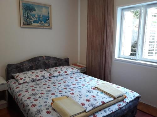 a bedroom with a bed with a blanket and a window at Accommodation Vlaovic , free parking place and Wi&fi in Sutorina