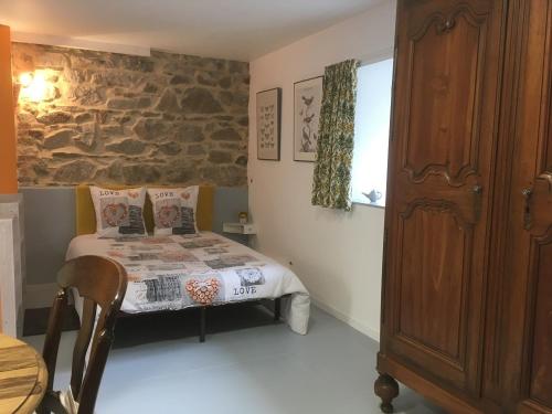 a bedroom with a bed and a stone wall at Moulin de la Fayolle in Blot-lʼÉglise