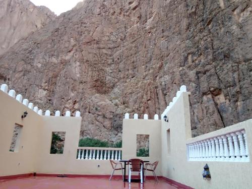 a room with a table and chairs in front of a mountain at Hotel De La Vallée in Aït Baha
