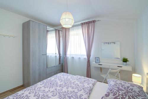 a bedroom with a bed and a desk and a window at Josipa & Jelena Apartment in Senj