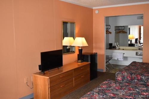 une chambre d'hôtel avec un lit et une télévision sur une commode dans l'établissement Thurman's Lodge, à Eureka Springs