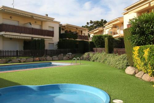 a swimming pool in a yard next to a house at Apartamentos Laura Mar in Palamós