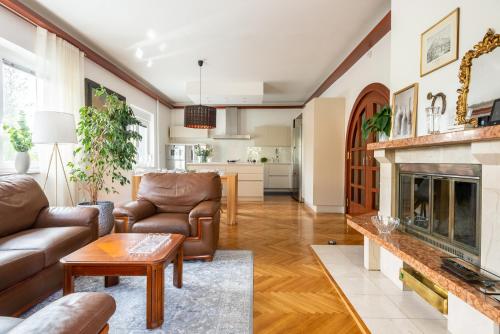 Una sala de estar con muebles de cuero y chimenea. en Vila Tivoli, en Liubliana