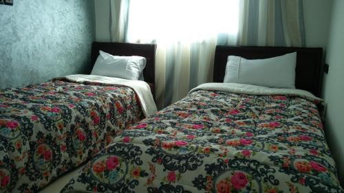 two beds sitting next to each other in a bedroom at LOGEMENT HOTEL et NAVETTE GRATUITE in Fès