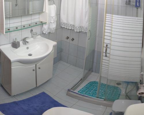 a white bathroom with a sink and a shower at Green Farm-small paradise! in Kalloní