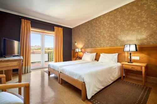 1 dormitorio con 1 cama grande y TV en Hotel Castrum Villae by Walk Hotels, en Castro Laboreiro