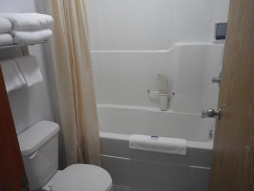 a bathroom with a white toilet and a bath tub at Alcan Motor Inn in Haines Junction