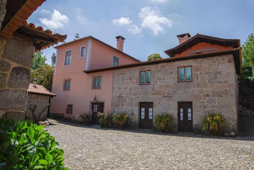 een groot roze gebouw met planten ervoor bij Casa do Telhado in Guimarães