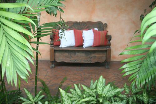 a bench with pillows in a room with plants at Hotel Ciudad Vieja in Guatemala