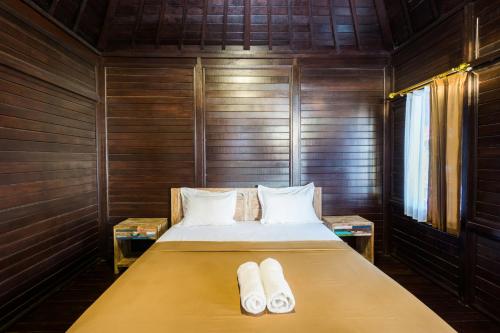 a bed in a wooden room with two pillows at Agung Lembongan Bungalow in Nusa Lembongan