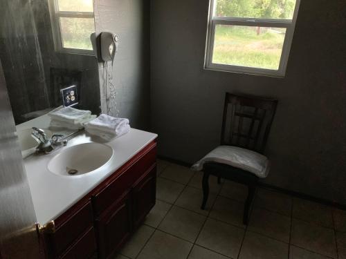 a bathroom with a sink and a chair and a window at Mountain Trail Lodge and Vacation Rentals in Oakhurst