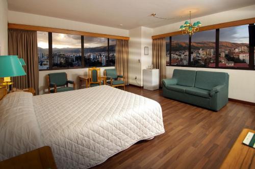 a hotel room with a bed and chairs and windows at Hotel Diplomat in Cochabamba