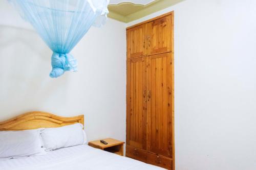 a bedroom with a bed and a wooden cabinet at Palm Hotel in Mbale