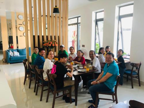 a group of people sitting around a table in a room at Peaceful House Hostel in Dong Hoi