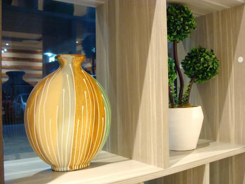 a vase sitting on a shelf with two potted plants at Airport Poddotel Inc. in Manila
