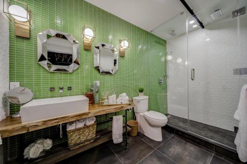 a bathroom with a sink and a toilet and green tiles at The Westlake in Toronto