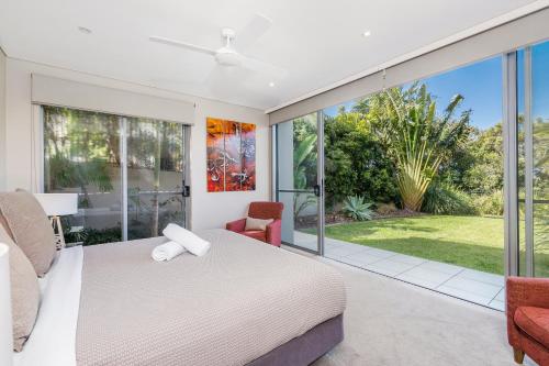 1 dormitorio con 1 cama y puertas correderas de cristal en Byron Bay Accom Unit 1 22 Mahogany Drive - Beach House 1 at Vue, en Byron Bay