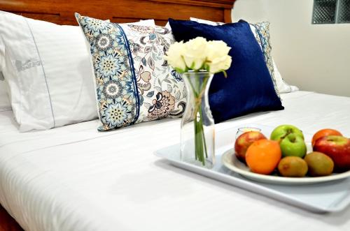 - un plateau avec un vase de fleurs et de fruits sur un lit dans l'établissement Hotel La Gran Esquina, à Puerto Boyacá