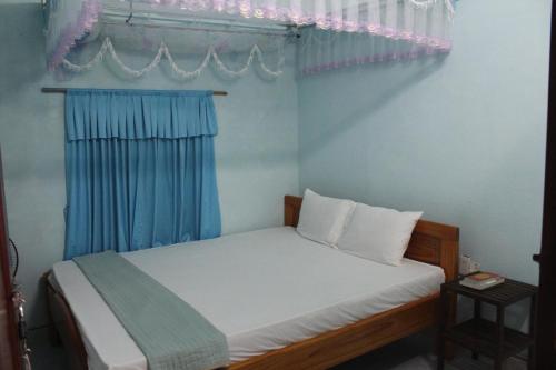 a small bedroom with a bed with blue curtains at Cham Island Smiles Homestay in Tân Hiệp