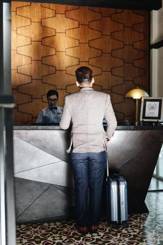 a woman standing in front of a mirror with a suitcase at The Henry Hotel Manila in Manila