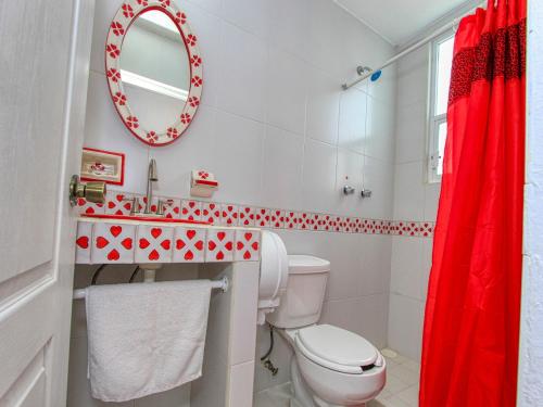 a bathroom with a toilet and a red shower curtain at Hotel Spa Maggic Home Panorámica in Guanajuato