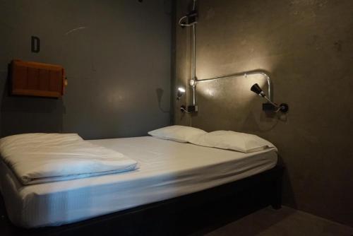 a small bed with white sheets and pillows in a room at Bed & Bike Hostel in Chiang Rai