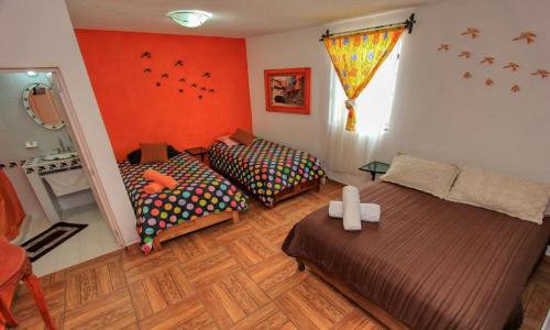 two beds in a room with orange walls at Hotel Spa Maggic Home Panorámica in Guanajuato
