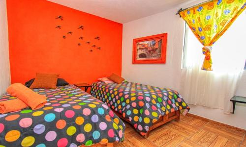 two beds in a room with orange walls at Hotel Spa Maggic Home Panorámica in Guanajuato