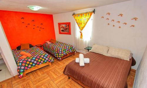 two beds in a room with orange walls at Hotel Spa Maggic Home Panorámica in Guanajuato
