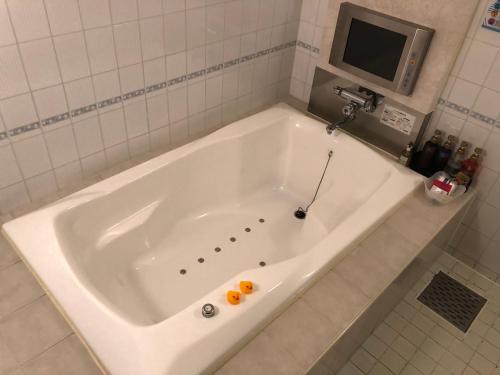 a white bath tub in a bathroom with a tv at Restay Mito (Adult Only) in Mito