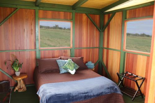 a bed in a room with two windows at The Inn at Kulaniapia Falls in Hilo