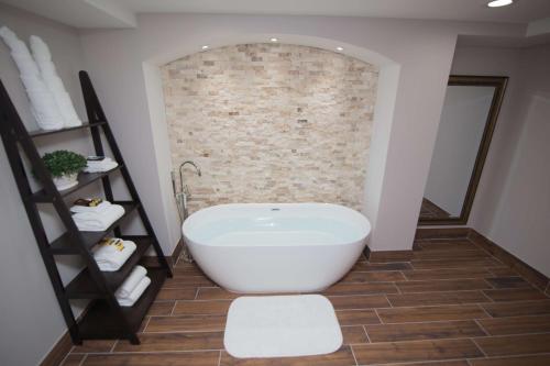 a bathroom with a white tub and a brick wall at Best Western Plus Fairfield Executive Inn in Fairfield