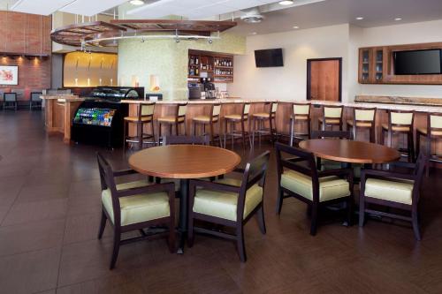 a bar with wooden tables and chairs in a restaurant at Hyatt Place Phoenix/ Mesa in Mesa