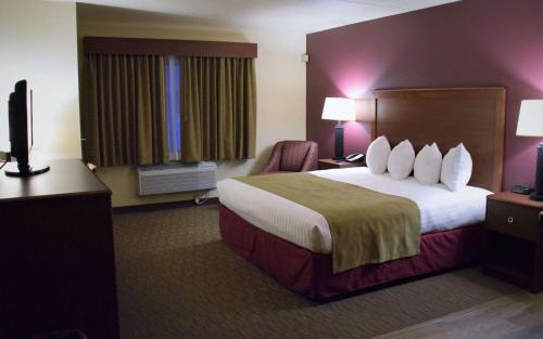 a hotel room with a large bed and a chair at AmericInn by Wyndham Merrill in Merrill