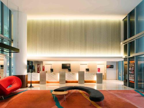 a living room with a red chair and a table at Ibis Singapore on Bencoolen - Newly Renovated in Singapore