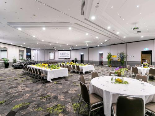 a banquet hall with white tables and chairs at Novotel Sydney International Airport in Sydney