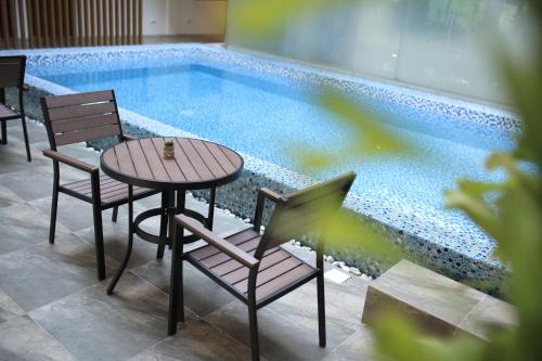 a table and chairs next to a swimming pool at SureStay Plus Hotel by Best Western AC LUXE Angeles City in Angeles