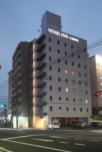 a tall white building with a sign on it at Vessel Inn Hiroshima Station in Hiroshima