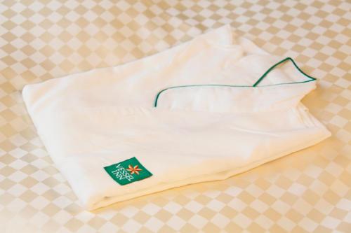 a white pillow with a green label on it at Vessel Inn Hiroshima Station in Hiroshima