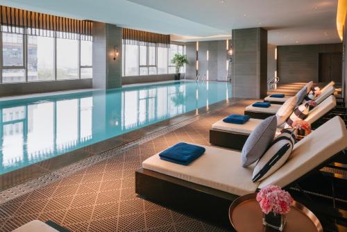 una piscina en una habitación de hotel con una fila de camas en Pullman Shanghai Qingpu Excellence en Shanghái