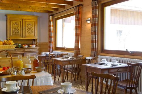 a restaurant with wooden tables and chairs and windows at Logis Hotel & Spa Beau-Site in Saint-Jean-de-Sixt